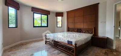 Spacious bedroom with elegant wooden bed and large windows offering natural light