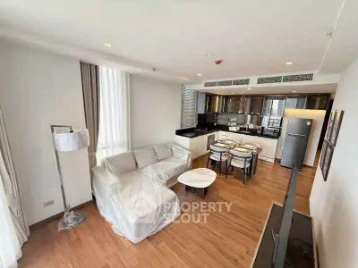 Modern open-plan living room with sleek kitchen and dining area, featuring hardwood floors and contemporary furnishings.