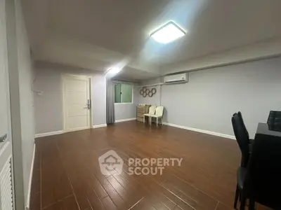 Spacious living room with wooden flooring and modern lighting in a contemporary apartment.