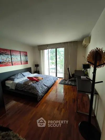 Spacious bedroom with modern decor and large window overlooking greenery, featuring a cozy bed and stylish furnishings.