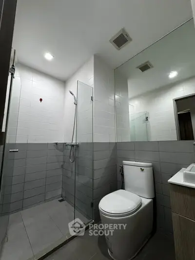 Modern bathroom with sleek design, featuring a glass-enclosed shower and contemporary fixtures.