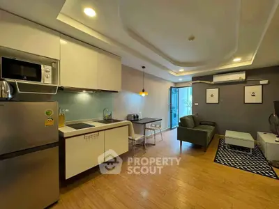 Modern open-layout living room with kitchen, featuring sleek appliances and stylish decor.