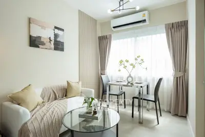 Modern living room with elegant decor and natural light, featuring a cozy sofa and dining area.