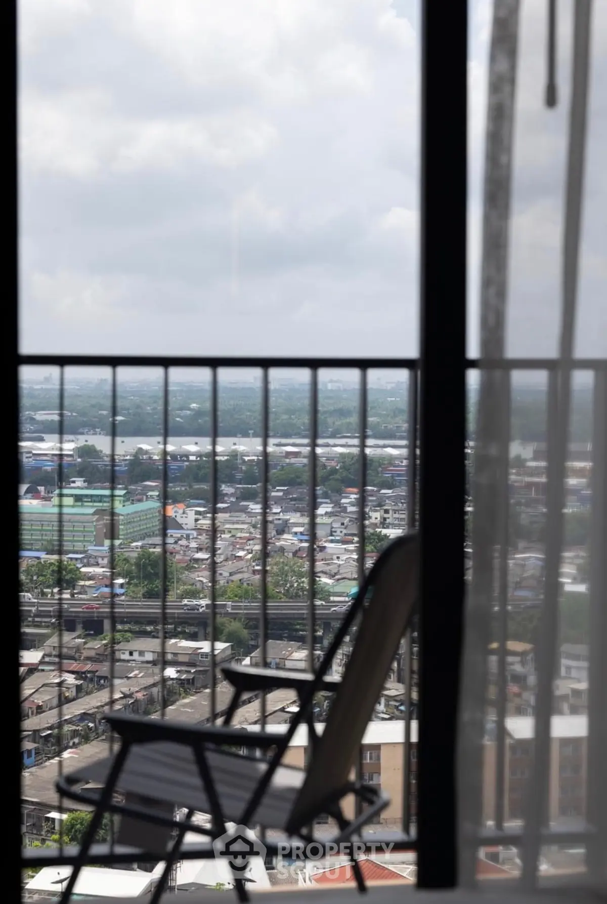Stunning cityscape view from a high-rise balcony with chair