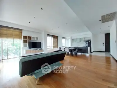 Expansive open-plan living space with gleaming hardwood floors, modern kitchen, and ample natural light, perfect for entertaining and relaxation.