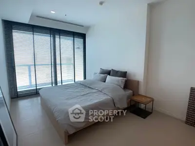 Modern bedroom with large windows and stylish decor in a contemporary apartment.