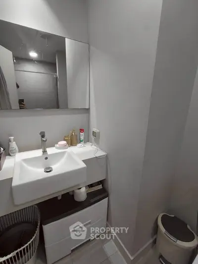 Modern bathroom with sleek sink and mirror, featuring minimalist design and neutral tones.