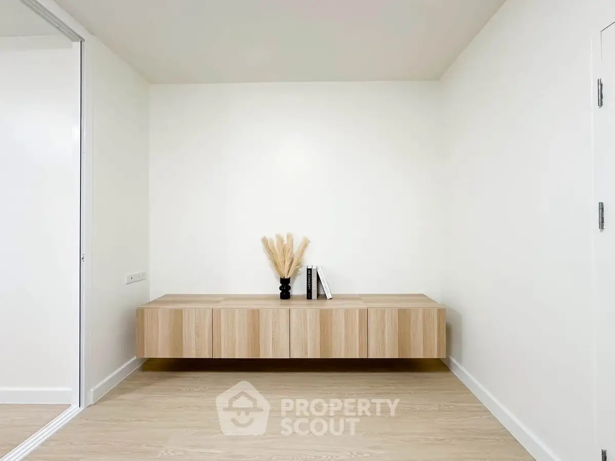 Minimalist interior with floating wooden cabinet and decorative vase in modern apartment.