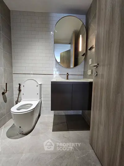 Modern bathroom with sleek design, featuring a wall-mounted vanity and oval mirror.