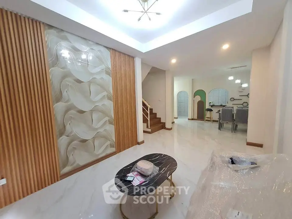Modern living room with elegant decor and open dining area, featuring stylish lighting and marble table.