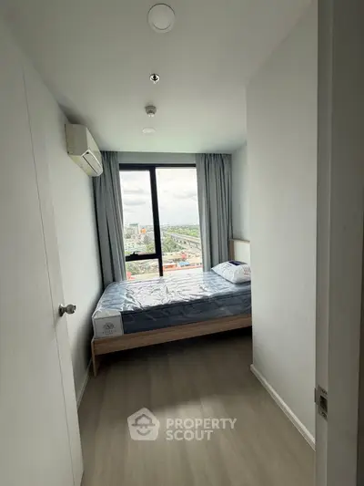 Modern bedroom with large window offering stunning city view, featuring minimalist design and air conditioning.