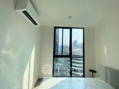 Modern bedroom with large window offering stunning city view and natural light.