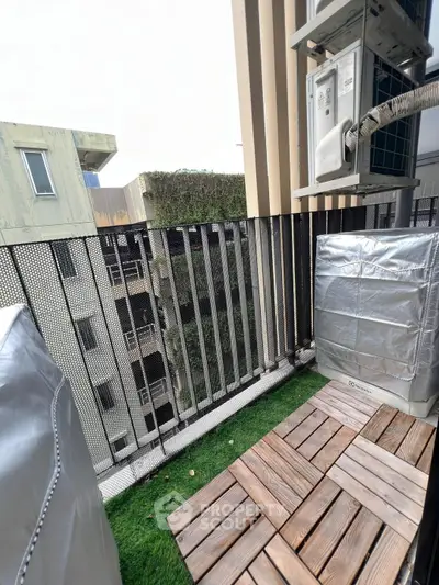 Charming small balcony with artificial grass and wooden decking, perfect for urban relaxation.