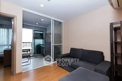 Modern living room with cozy sofa and sliding glass doors leading to a balcony with city view.