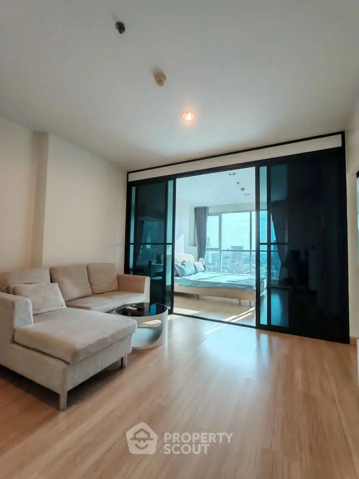 Modern living room with sliding glass doors leading to a bright bedroom with city view.