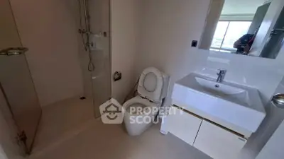 Modern bathroom with sleek fixtures and glass shower in a contemporary apartment.