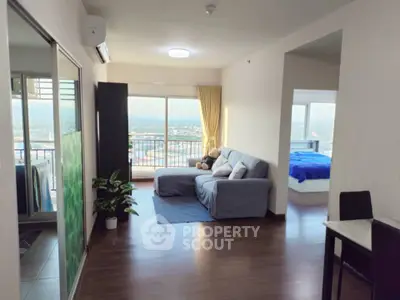 Spacious open-plan living room with balcony and scenic view, featuring cozy seating and modern decor.