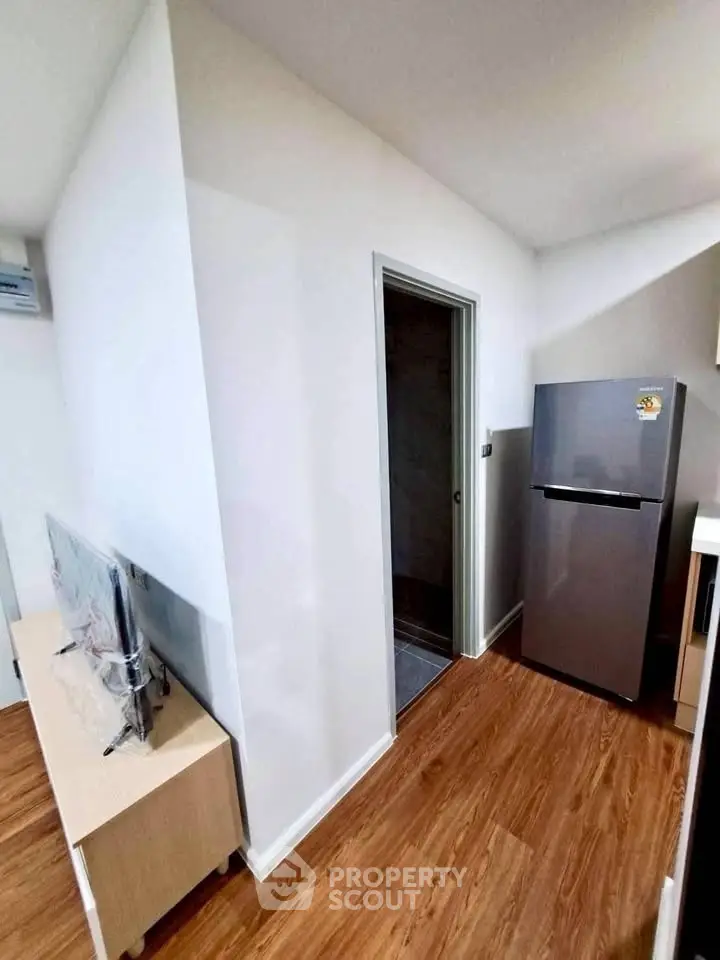 Modern apartment interior with sleek fridge and TV on wooden flooring