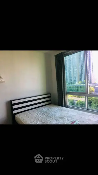 Bright bedroom with large window offering city view and natural light