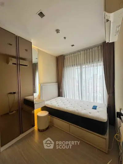 Modern bedroom with large window and mirrored wardrobe in stylish apartment.