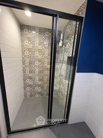 Modern bathroom with stylish patterned tiles and glass shower enclosure