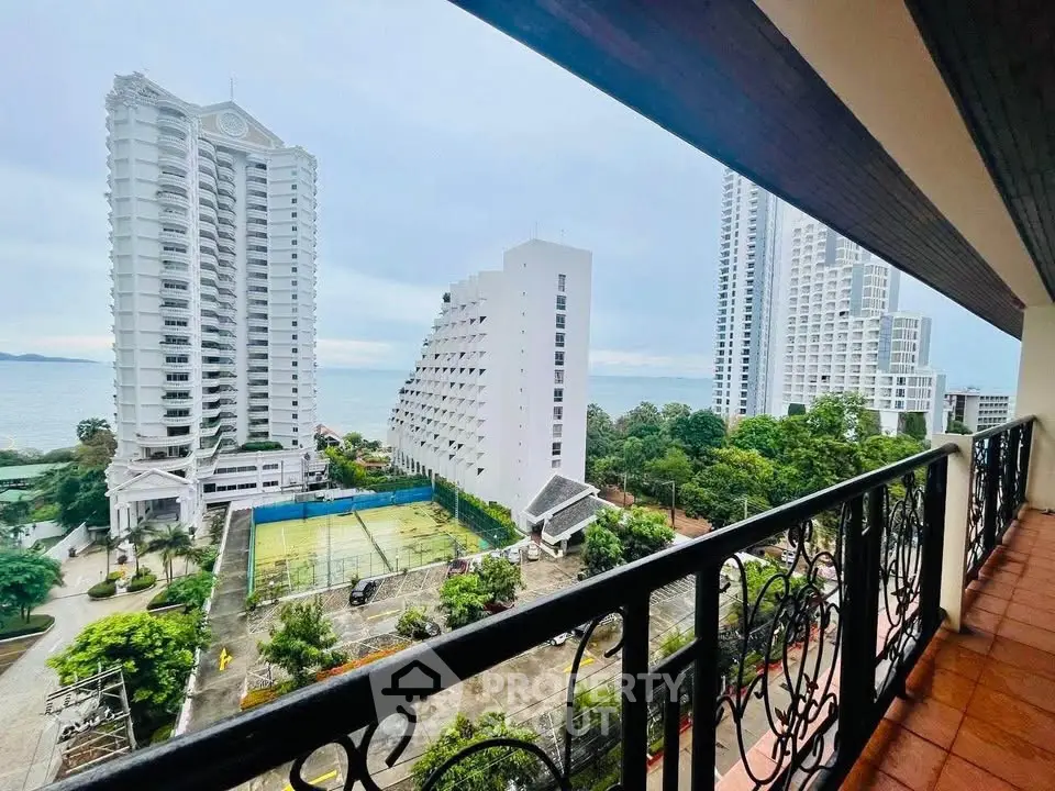 Stunning ocean view from a high-rise balcony overlooking tennis courts and modern buildings.