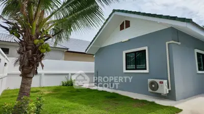 Charming single-story home with lush green lawn and palm tree, perfect for tropical living.