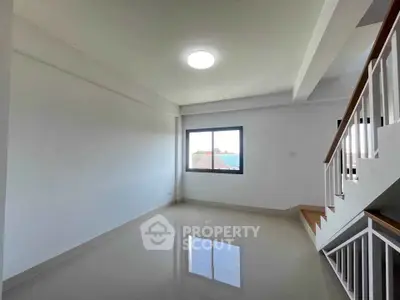 Spacious and bright living room with modern staircase and large window view.