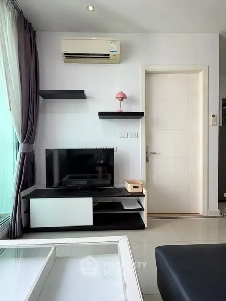 Modern living room with sleek furniture and air conditioning, featuring a stylish TV setup and elegant decor.