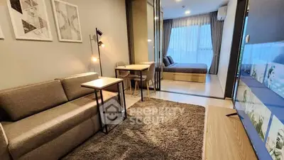 Modern living room with cozy sofa, stylish decor, and view into a chic bedroom through glass doors.