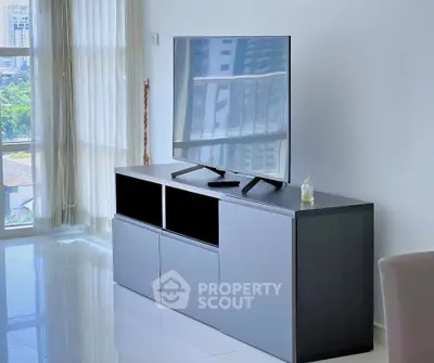 Modern living room with sleek TV stand and large windows offering city views.