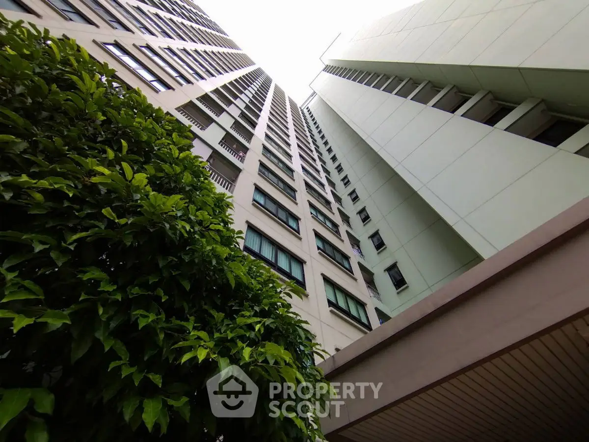 Stunning upward view of modern high-rise building with lush greenery