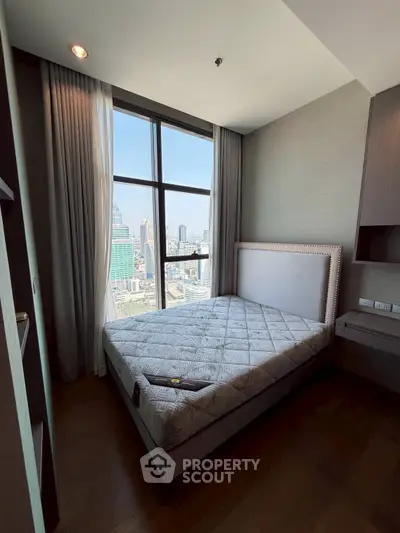 Modern bedroom with city view, featuring large window and stylish decor in a high-rise apartment.