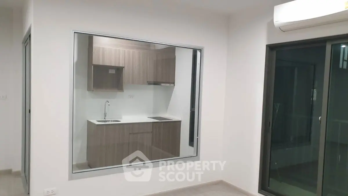 Modern apartment with sleek kitchen and large window, featuring contemporary design and ample natural light.