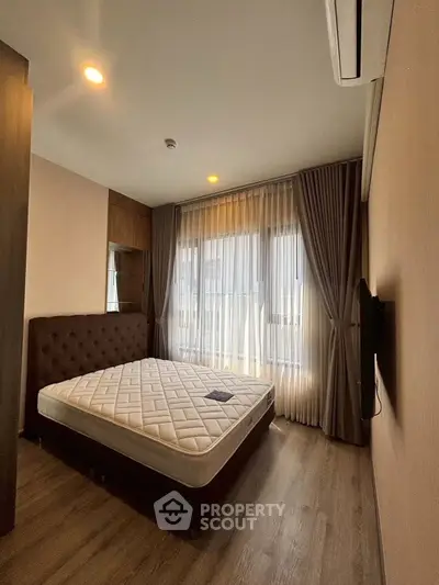 Spacious bedroom with large windows and modern decor, featuring a comfortable bed and elegant curtains.