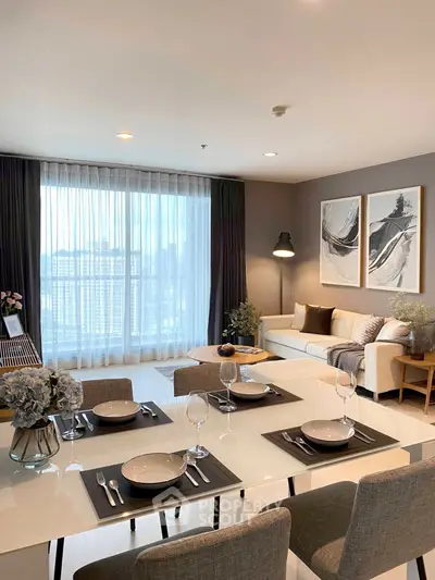 Elegant modern living room with dining area, large windows, and stylish decor in a high-rise apartment.