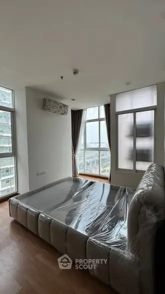 Spacious bedroom with large windows and modern bed in high-rise apartment