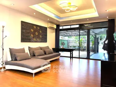 Spacious modern living room with stylish decor and large windows opening to a patio.