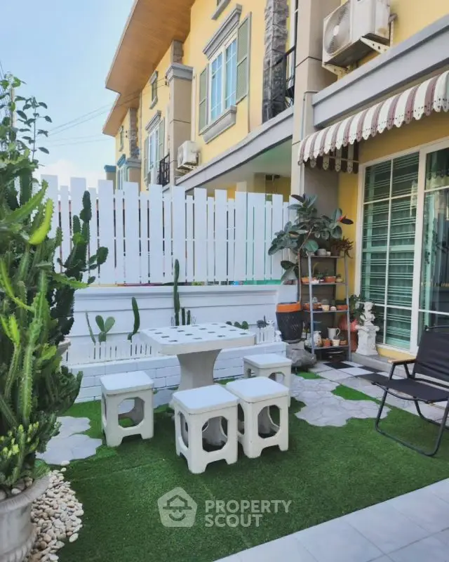 Charming townhouse exterior with cozy garden seating area and lush greenery.