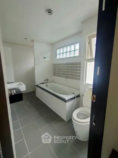 Modern bathroom with bathtub and sleek design, featuring large window for natural light.