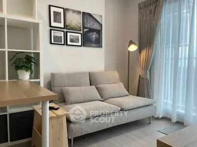 Modern living room with cozy sofa, stylish decor, and natural light from large window.