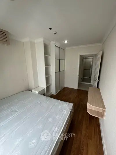 Spacious bedroom with wooden flooring and built-in wardrobe