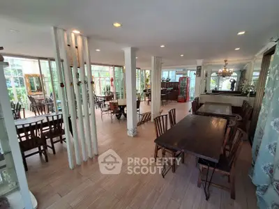 Spacious dining area with wooden tables and chairs, large windows, and elegant decor.