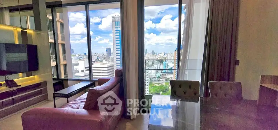 Luxurious living room with stunning city view from high-rise apartment, featuring modern furniture and large windows.