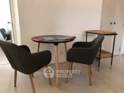 Modern dining area with stylish chairs and round table in a cozy apartment setting.