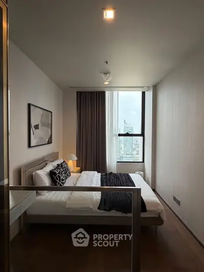 Modern bedroom with city view, featuring elegant decor and natural light.