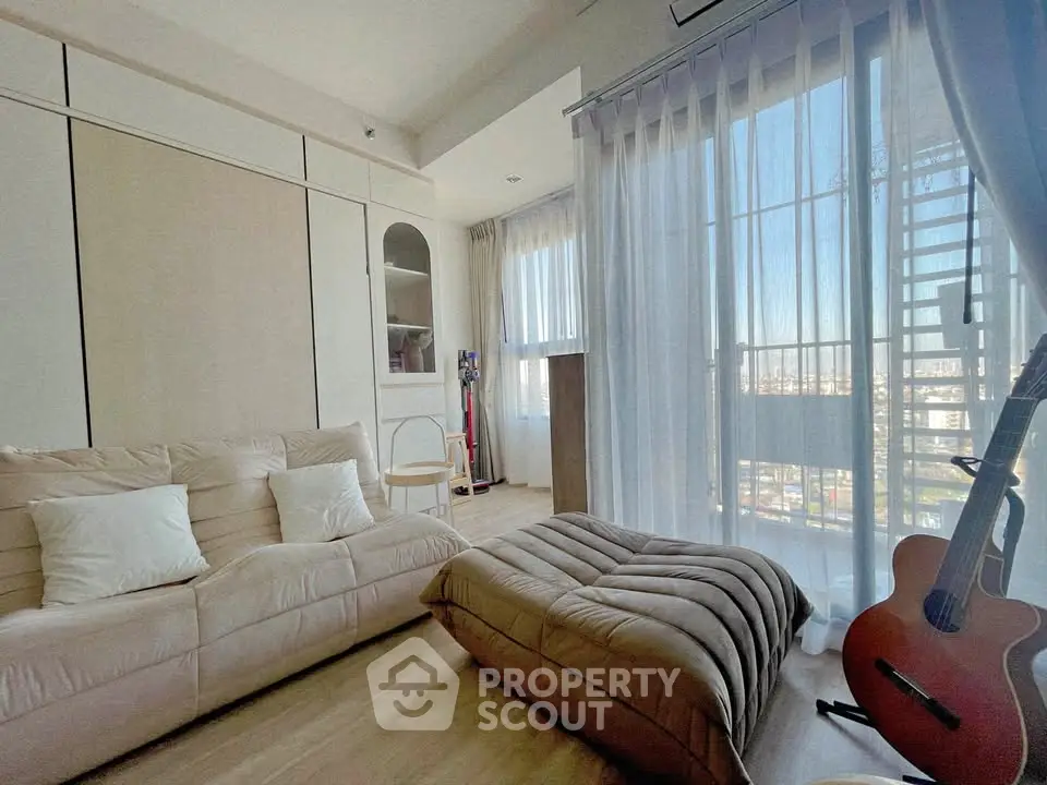 Cozy living room with plush seating and large windows offering a stunning city view.