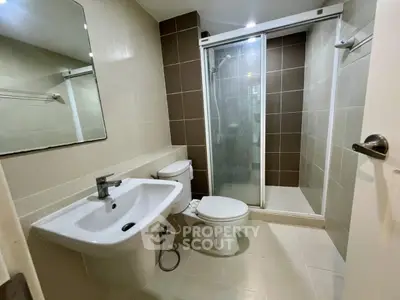 Modern bathroom with sleek fixtures and glass shower enclosure in a contemporary apartment.