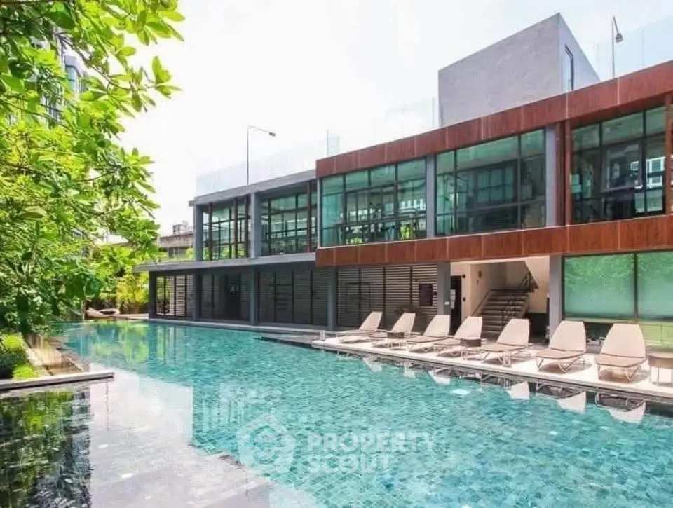 Luxurious modern building with a stunning outdoor pool and sun loungers, perfect for relaxation and leisure.