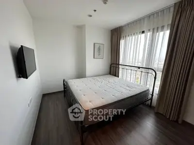 Spacious bedroom with large window and modern decor in a high-rise apartment.